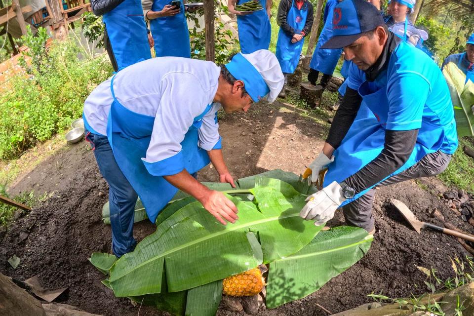 Grupo de viajeros preparando pachamanca cubriendo ingredientes con hojas de plátano | TreXperience
