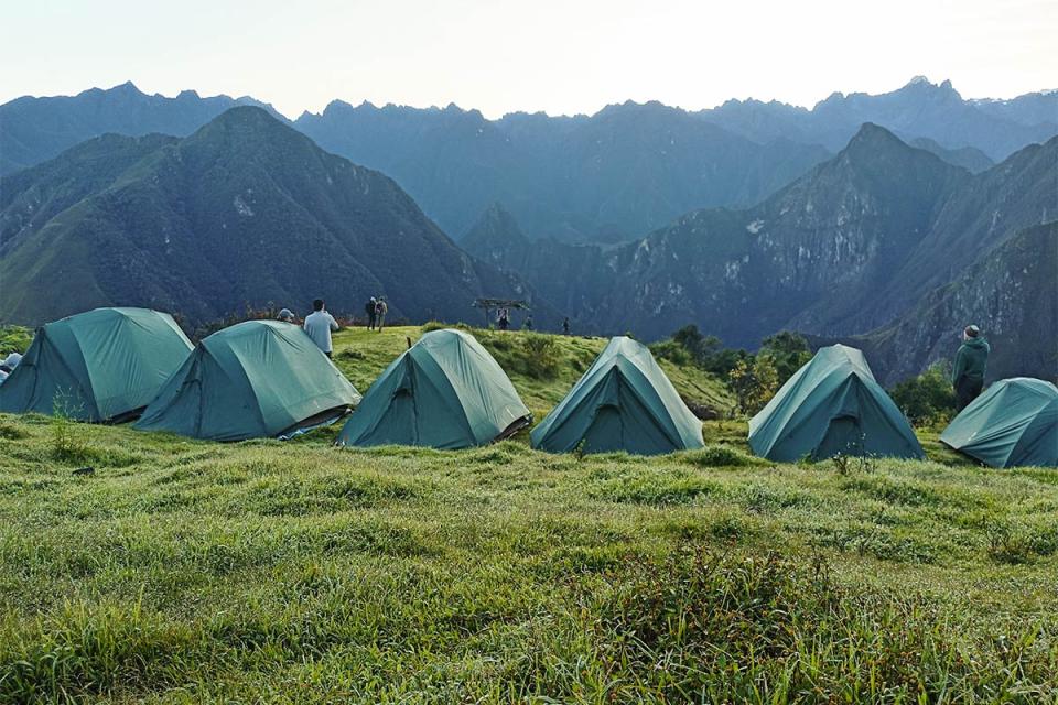 Filas de tiendas de campaña instaladas en el campamento de Patallacta junto a un valle frente a montañas rocosas | TreXperience