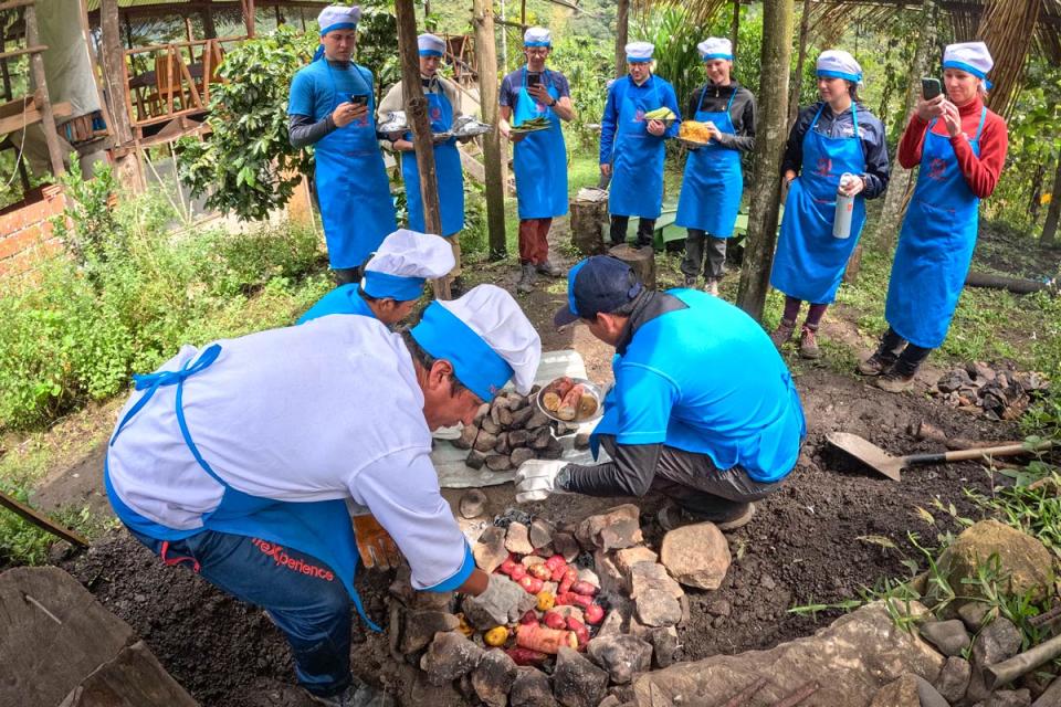 Group of people preparing pachamanca with stones in an outdoor oven | TreXperience