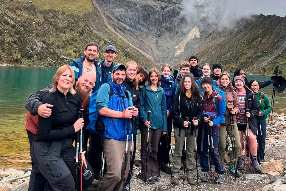 Traveler group posing in front of turquoise Humantay Lake | TreXperience