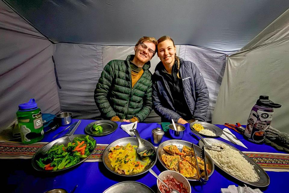 Two travelers enjoying a served dinner inside a camping tent during a hike | TreXperience