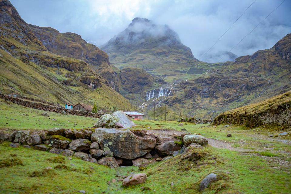 Panoramic view of a mountain waterfall surrounded by a misty Andean landscape during a hike | TreXperience