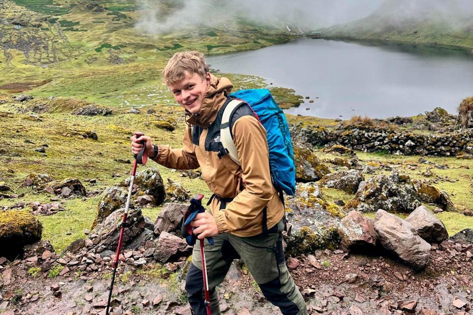 Hiker walking with trekking poles beside a mountain lake on Lares Trek | TreXperience