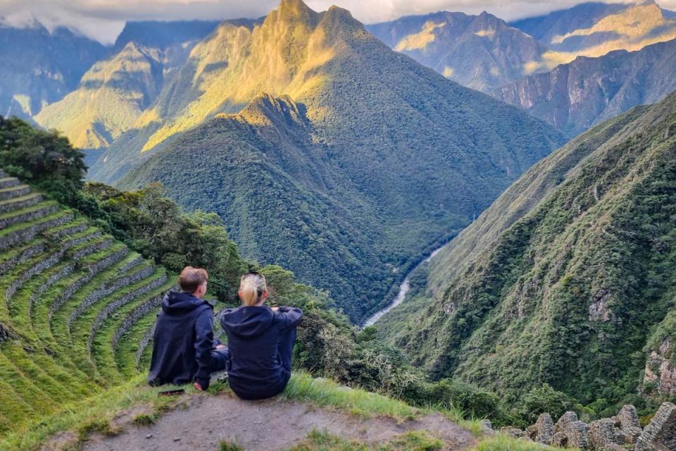 Dos viajeros sentados junto en el Inti Punku viendo a Machu Picchu | TreXperience
