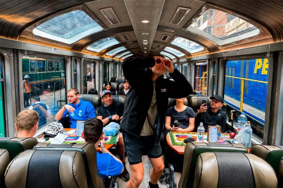 Travelers inside a panoramic train while a standing passenger looks up through the roof windows | TreXperience