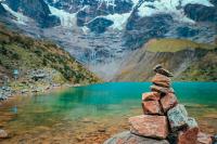 Montículo de piedras junto a la Laguna Humantay con aguas turquesas y montañas nevadas al fondo (tour a la Laguna Humantay, día completo) | TreXperience