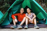 Two hikers sitting at the entrance of a green tent at camp, Inca Trail to Machu Picchu 4 Days | TreXperience