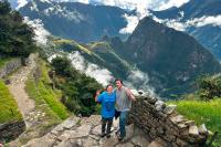 Pareja de viajeros posando con vista panorámica de Machu Picchu desde el Inti Punku | TreXperience