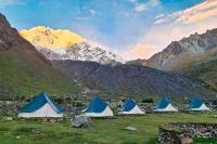 Campsite tents on a grassy field with rocky mountains and Nevado Salkantay in the background, Salkantay Trek 4 Days to Machu Picchu | TreXperience