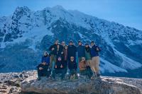 Group of hikers poses on a large rock with Nevado Salkantay in the background under a blue sky, Salkantay Trek 5 Days to Machu Picchu | TreXperience