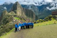 Group in blue shirts poses at Machu Picchu with terraces and Huayna Picchu behind, Cachicata Inca Quarry Trek to Machu Picchu 4 Days 3 Nights | TreXperience