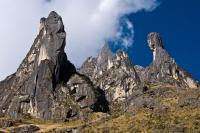 Tall dark rock formations at the Ccaccahuara Stone Forest under a blue sky with clouds, Cachicata Inca Quarry Trek to Machu Picchu 4 Days 3 Nights | TreXperience