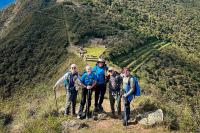 Grupo de excursionistas posa en un mirador con bastones y mochilas, con los andenes y recintos de Choquequirao al fondo, Choquequirao Trek 4 días 3 noches | TreXperience