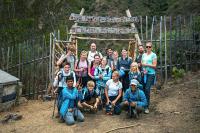 Grupo de excursionistas posa bajo el letrero “Welcome Bienvenido Choquequirao” en una entrada rústica de madera, Choquequirao Trek 4 días 3 noches | TreXperience