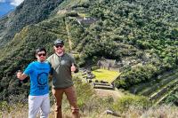 Two hikers pose with thumbs up in front of Choquequirao terraces and stone buildings on the hillside, Choquequirao Trek 5 Days 4 Nights | TreXperience