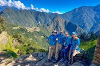 Grupo con polos azules posa en un mirador de piedra con Machu Picchu a lo lejos y montañas verdes alrededor, Huchuy Qosqo y Camino Inca Corto 4 días | TreXperience