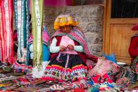 Person weaving a textile while wearing traditional Andean clothing at a handicraft market | TreXperience