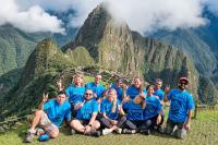 Grupo de viajeros con polos de TreXperience posando frente a Machu Picchu | TreXperience