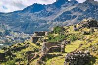 Panoramic view of a stone archaeological site with circular structures on a hillside surrounded by Andean mountains | TreXperience