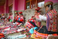 Group of people making textiles while wearing traditional Andean clothing at a handicraft market | TreXperience