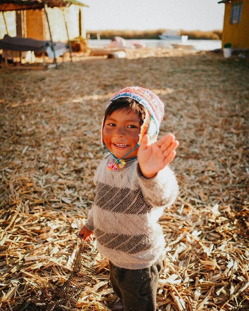 Peruvian child smiling at the camera in Uros Islands Peru | TreXperience